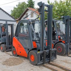 Many Electric Forklift Trucks Parked in Yard